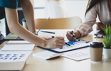 An financial analyst and a colleague examine a document together in an office setting