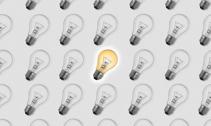 Black and white lightbulbs fill the frame with one yellow lightbulb in the center.
