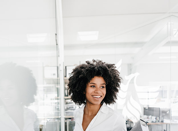 A smiling businesswoman in a white shirt handing someone a grey binder