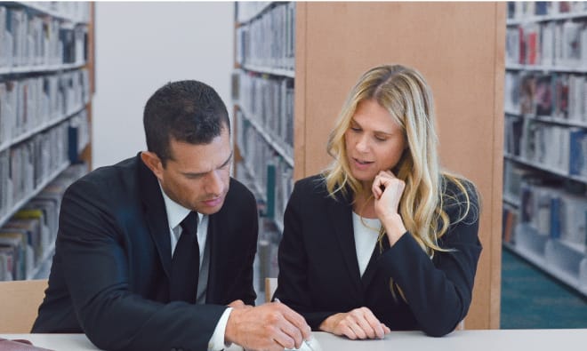 Business man and woman conversing in a library