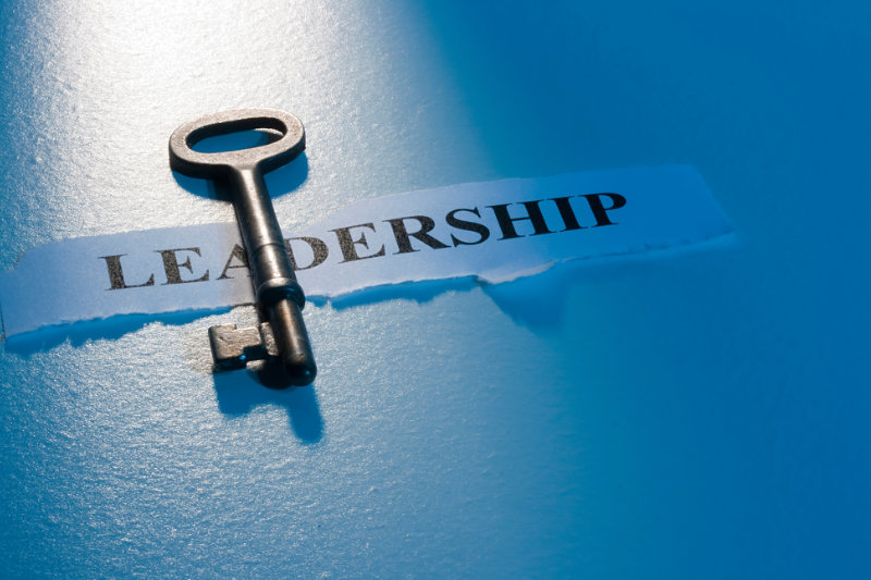 Black victorian styles key on blue background withe word "leadership" behind it