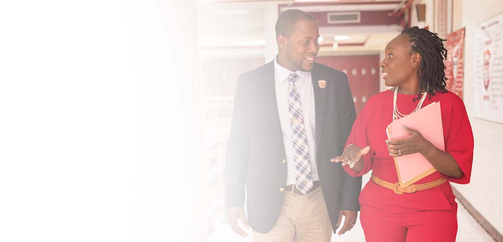 Two faculty members walk through a school hallway