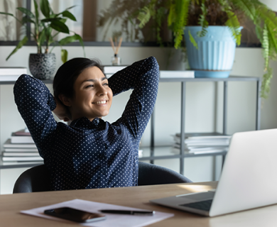 Woman relaxes, smiling while working on her laptop