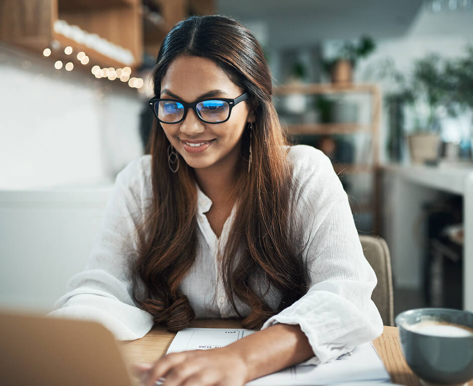 a woman reviews career opportunities on her laptop at her kitchen table.